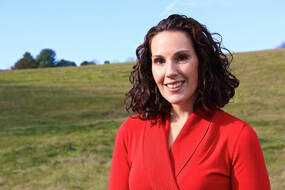 Erin Zaffini pictured in red shirt with a green field and sky in the background