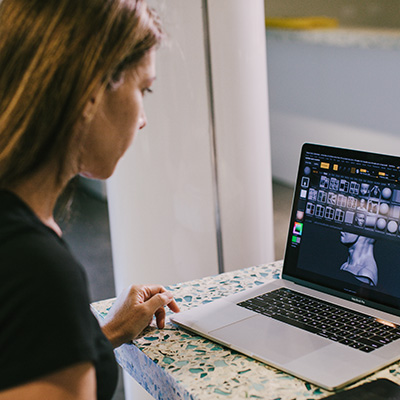 A woman, left, looking at a laptop displaying multiple images, on the right.