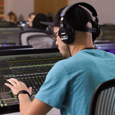 A student working on a mixing console in the studio