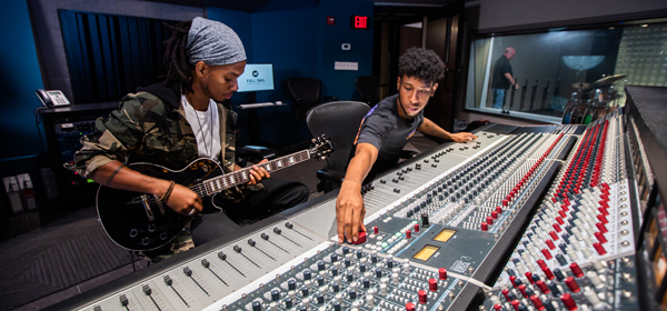 Students working on a mixing console with a guitar.
