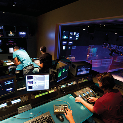 Production mixing studio at Full Sail with four engineers mixing, various screens around them, and a large window in the background